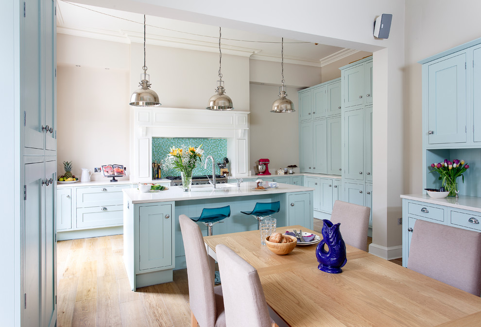 Klassische Küche in U-Form mit Unterbauwaschbecken, Schrankfronten im Shaker-Stil, weißen Schränken, Küchenrückwand in Blau, Küchengeräten aus Edelstahl, hellem Holzboden, Kücheninsel und beigem Boden in Edinburgh