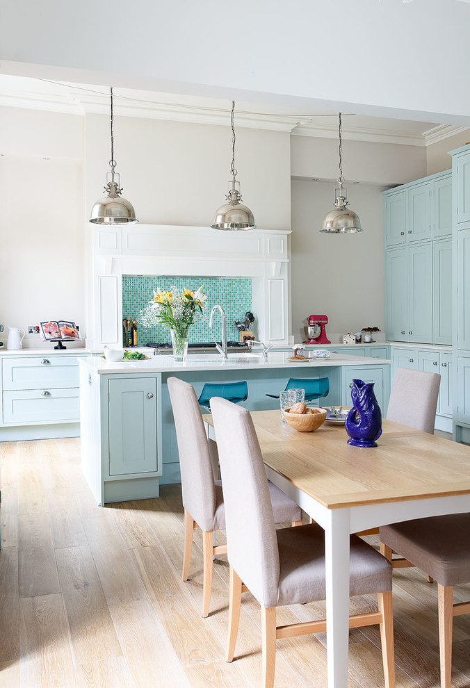 Photo of a traditional l-shaped kitchen/diner in Edinburgh with shaker cabinets, blue cabinets, blue splashback, mosaic tiled splashback, light hardwood flooring and an island.
