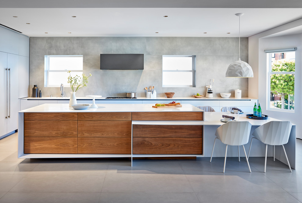 Modern inredning av ett stort vit vitt kök, med en integrerad diskho, släta luckor, grått stänkskydd, vita vitvaror, en köksö, grått golv och grå skåp