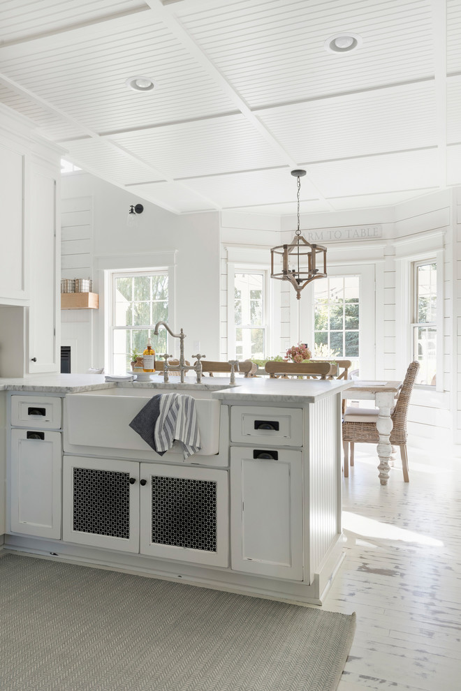 Lantlig inredning av ett mellanstort vit vitt kök, med en rustik diskho, luckor med profilerade fronter, vita skåp, vitt stänkskydd, stänkskydd i trä, målat trägolv, en köksö och vitt golv