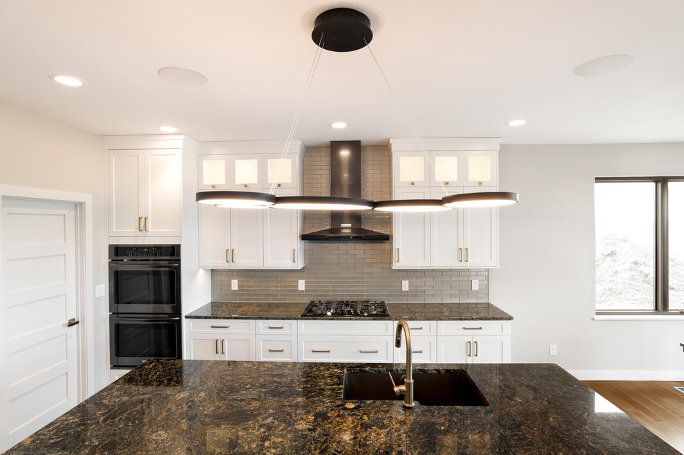 Eat-in kitchen - large contemporary single-wall medium tone wood floor and brown floor eat-in kitchen idea in Other with a double-bowl sink, shaker cabinets, white cabinets, granite countertops, beige backsplash, stainless steel appliances, an island and black countertops