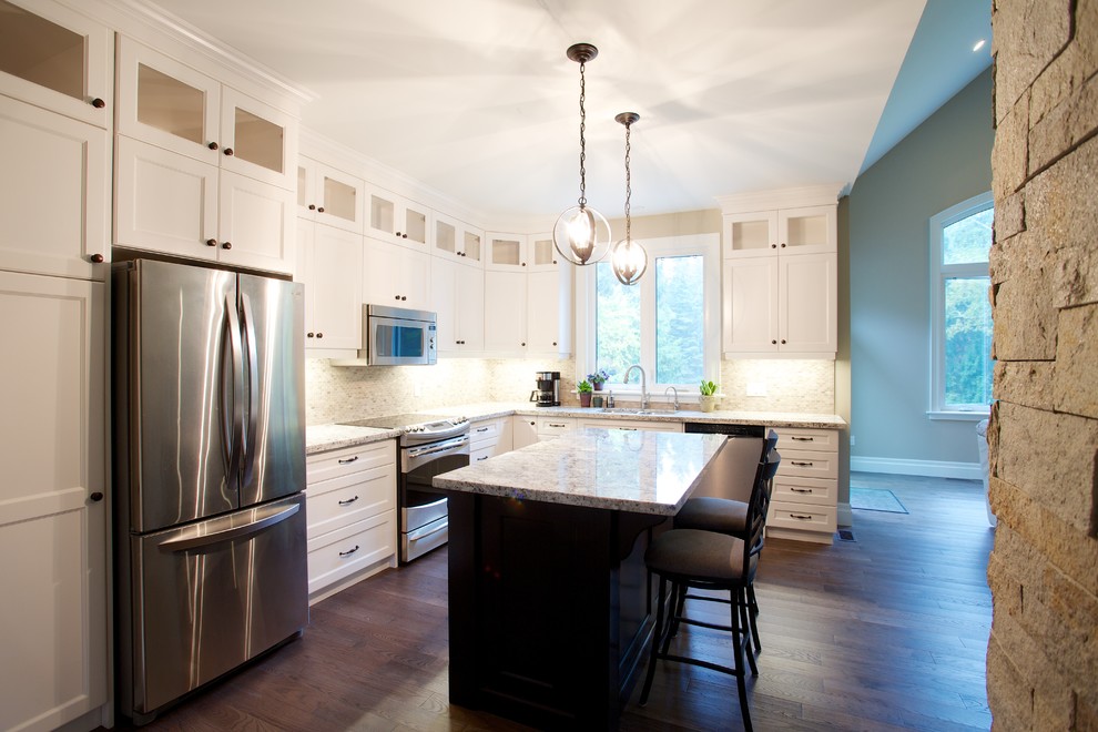 Example of a mid-sized transitional l-shaped medium tone wood floor eat-in kitchen design in Toronto with a drop-in sink, flat-panel cabinets, white cabinets, granite countertops, brown backsplash, subway tile backsplash, stainless steel appliances and an island