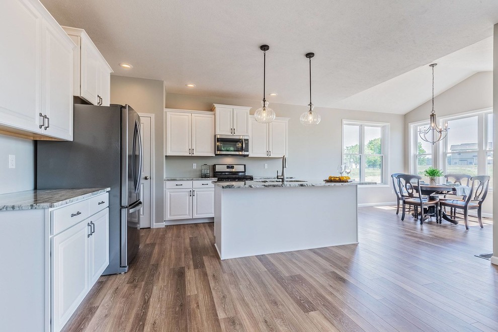Large farmhouse l-shaped light wood floor and brown floor eat-in kitchen photo in New York with an undermount sink, raised-panel cabinets, white cabinets, granite countertops, stainless steel appliances, an island and multicolored countertops