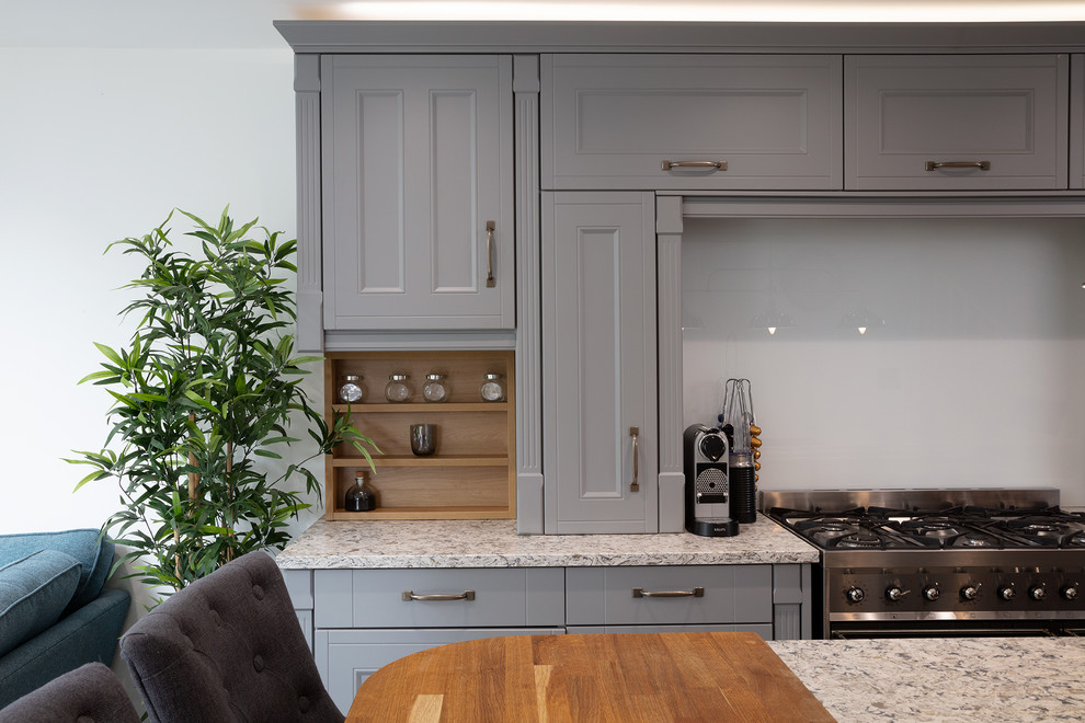 Cette photo montre une cuisine ouverte linéaire tendance de taille moyenne avec des portes de placard grises, une crédence grise et îlot.