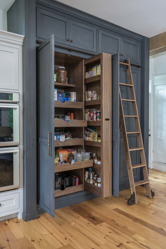 Cette photo montre une grande cuisine chic avec un électroménager en acier inoxydable, un sol en bois brun et un placard à porte shaker.
