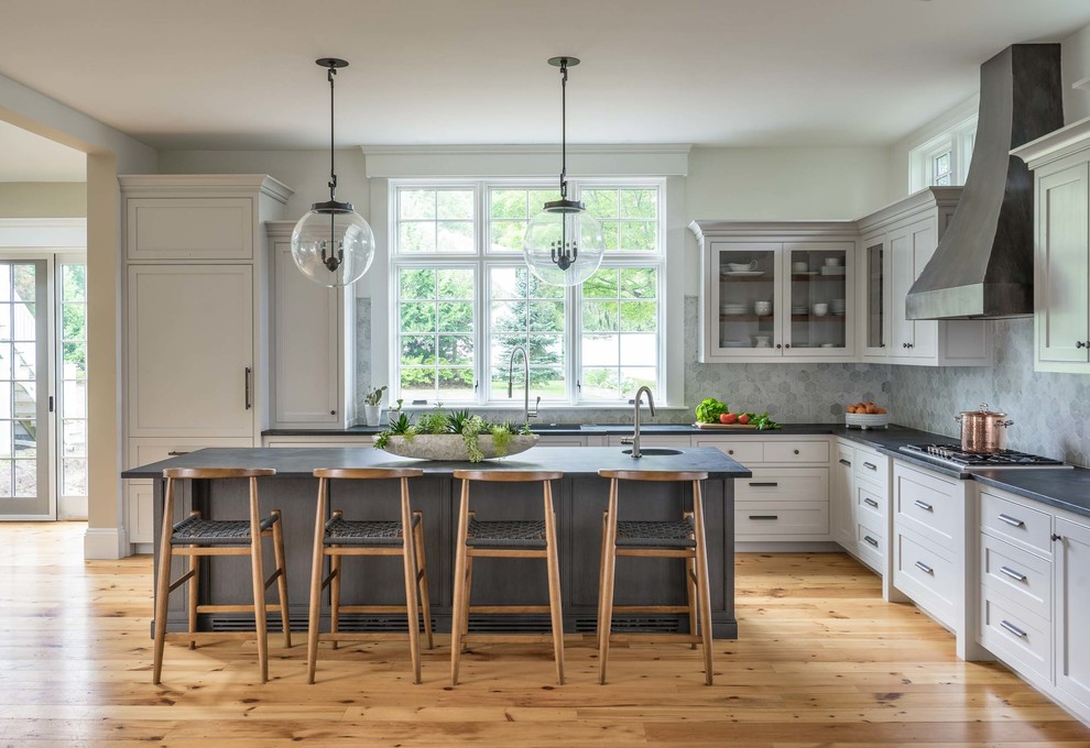 Große Klassische Küche in L-Form mit weißen Schränken, Speckstein-Arbeitsplatte, Küchenrückwand in Grau, Rückwand aus Keramikfliesen, braunem Holzboden, Kücheninsel, Glasfronten und Waschbecken in Boston