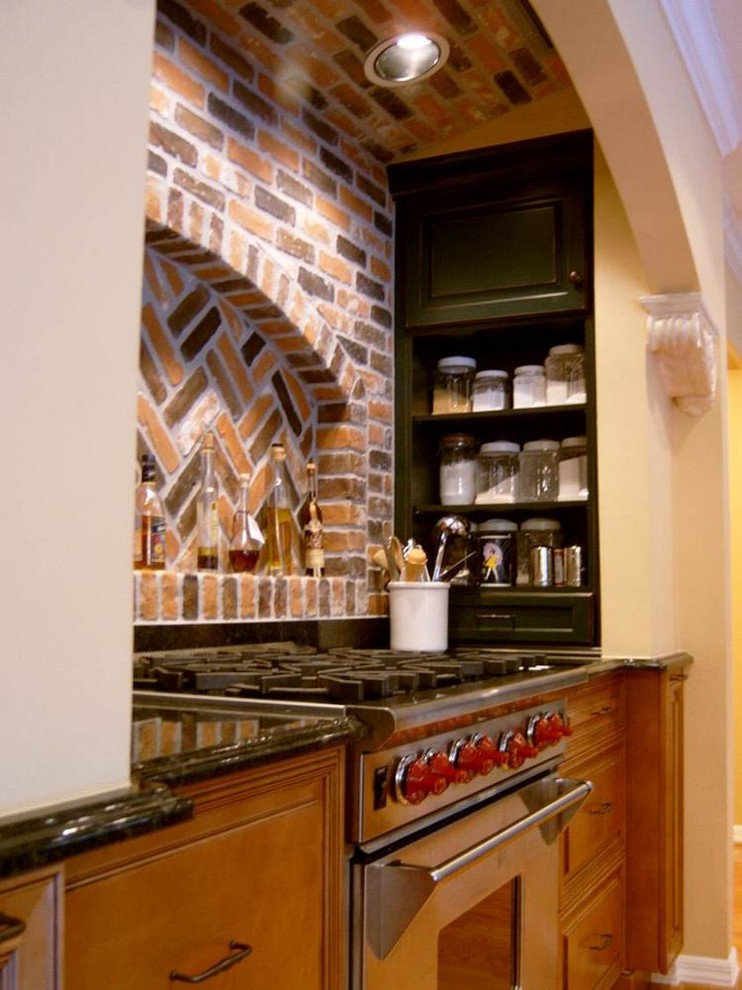 Klassische Wohnküche mit profilierten Schrankfronten, hellbraunen Holzschränken, Küchengeräten aus Edelstahl und braunem Holzboden in Sonstige