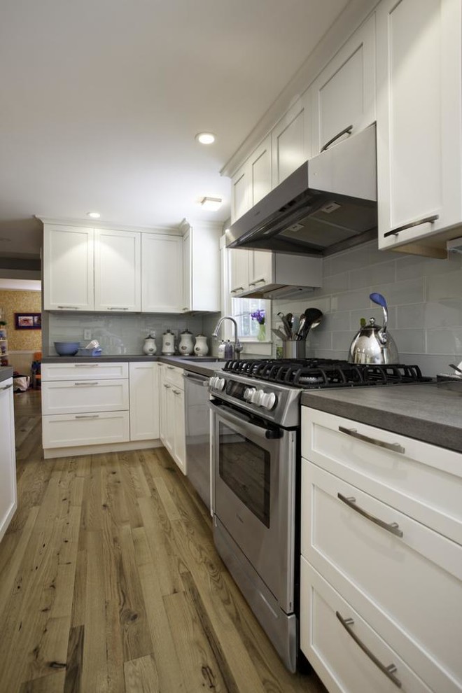 This is an example of a medium sized traditional l-shaped kitchen/diner in Other with flat-panel cabinets, white cabinets, composite countertops, stainless steel appliances, medium hardwood flooring and an island.