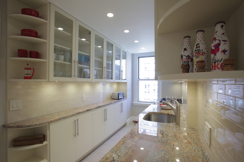 Example of a mid-sized transitional galley ceramic tile kitchen pantry design in New York with an undermount sink, glass-front cabinets, white cabinets, granite countertops, white backsplash, subway tile backsplash, stainless steel appliances and no island