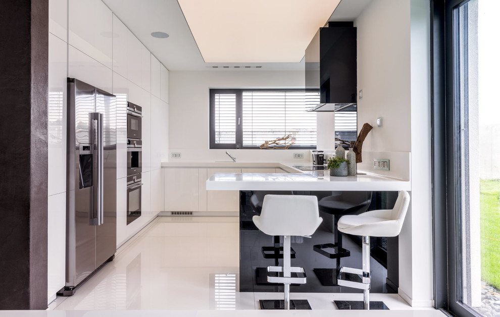 Idee per una cucina moderna di medie dimensioni con ante lisce, ante bianche, top in granito, paraspruzzi bianco, elettrodomestici neri, penisola, pavimento bianco e top bianco
