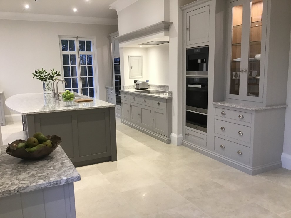 This is an example of an expansive contemporary single-wall kitchen/diner in Surrey with a submerged sink, shaker cabinets, grey cabinets, stainless steel appliances, ceramic flooring, an island, beige floors and grey worktops.