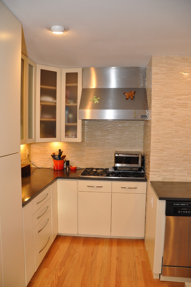 Aménagement d'une cuisine américaine parallèle contemporaine avec un évier encastré, des portes de placard blanches et un électroménager en acier inoxydable.