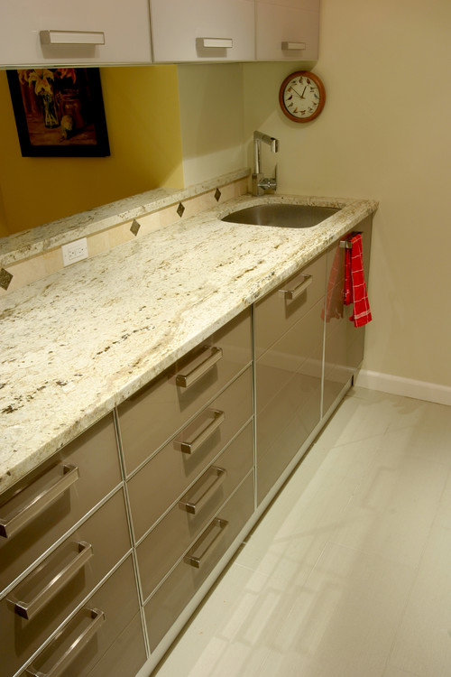 Kitchen countertop with granite surface and glossy Lacquer Finish For Cabinets featuring modern drawer handles