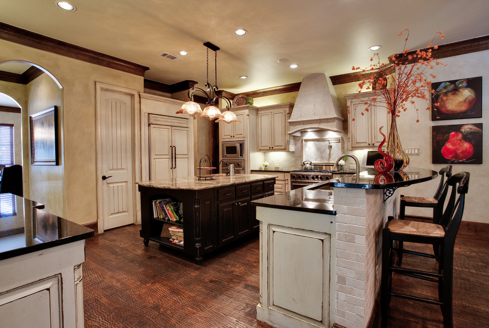 Klassisk inredning av ett stort kök, med en undermonterad diskho, beige skåp, granitbänkskiva, beige stänkskydd, stänkskydd i stenkakel, rostfria vitvaror och mellanmörkt trägolv