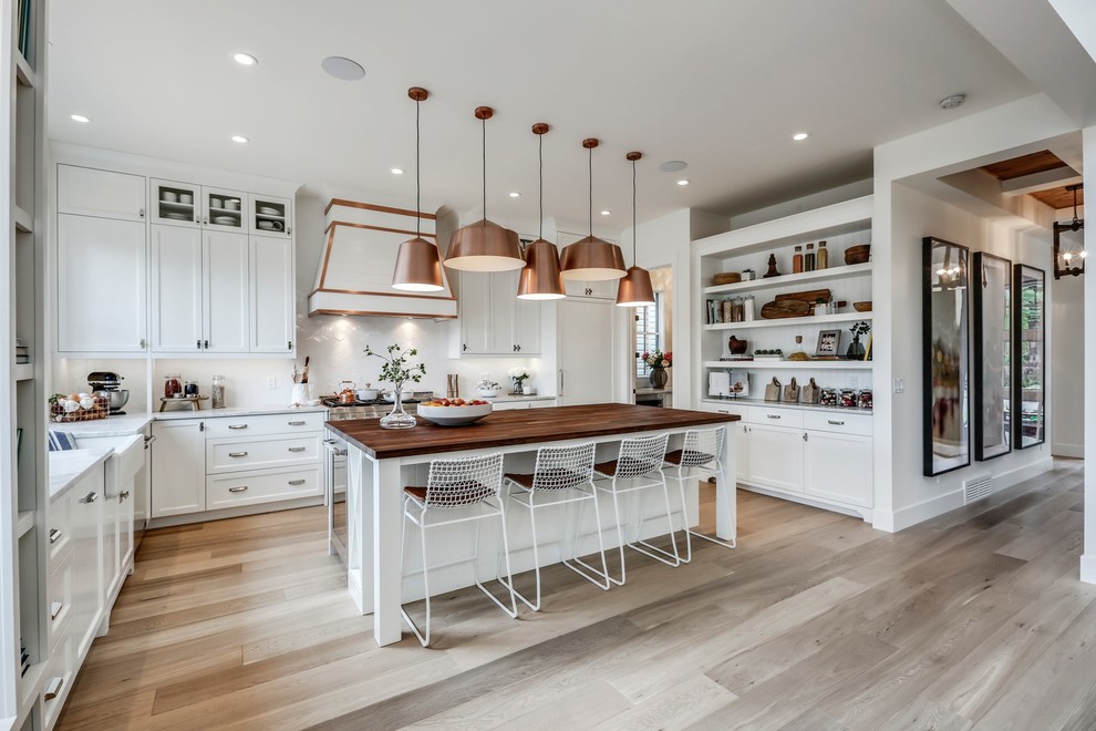 Large farmhouse u-shaped light wood floor and beige floor eat-in kitchen photo in Calgary with a farmhouse sink, shaker cabinets, white cabinets, wood countertops, ceramic backsplash, paneled appliances and an island