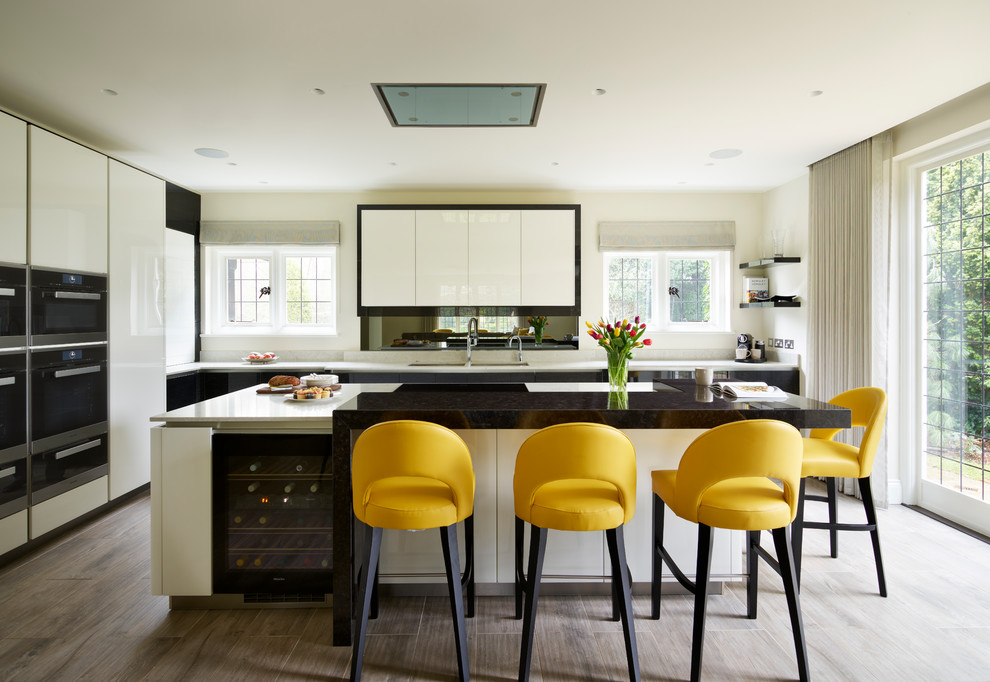 Foto di una cucina contemporanea di medie dimensioni con lavello sottopiano, ante lisce, ante bianche, pavimento grigio, paraspruzzi a specchio e elettrodomestici neri