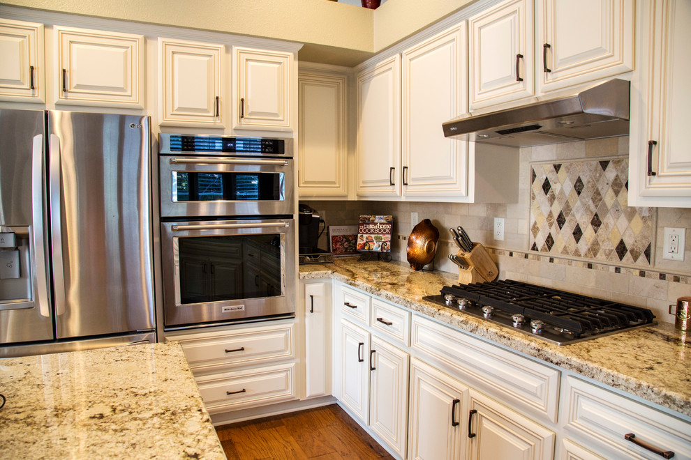 Bild på ett stort vintage kök, med en dubbel diskho, luckor med upphöjd panel, vita skåp, granitbänkskiva, beige stänkskydd, stänkskydd i kalk, rostfria vitvaror, mellanmörkt trägolv och en köksö