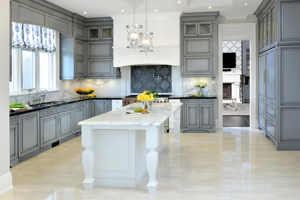Bild på ett stort vintage kök, med en undermonterad diskho, luckor med upphöjd panel, grå skåp, vitt stänkskydd, en köksö, marmorbänkskiva, stänkskydd i marmor, rostfria vitvaror och beiget golv
