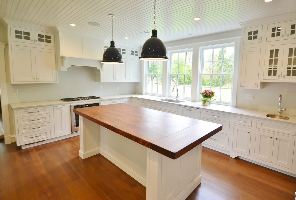 Expansive traditional l-shaped kitchen/diner in Philadelphia with a submerged sink, recessed-panel cabinets, white cabinets, wood worktops, stainless steel appliances, medium hardwood flooring, an island, brown floors and beige worktops.