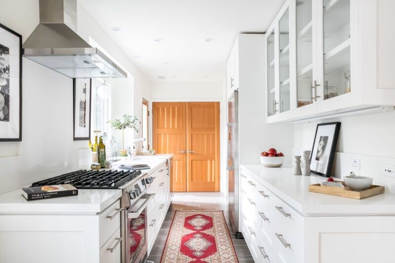 Medium sized classic galley kitchen/diner in Los Angeles with shaker cabinets, white cabinets, stainless steel appliances and light hardwood flooring.