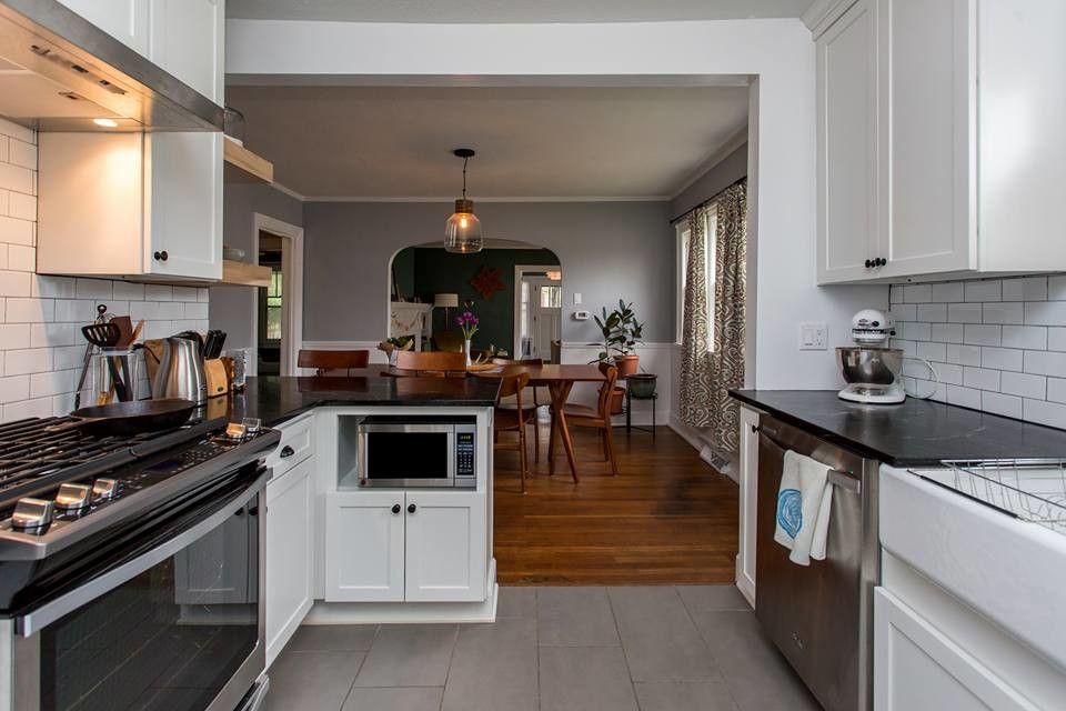 Eat-in kitchen - small transitional u-shaped cement tile floor and gray floor eat-in kitchen idea in Other with a farmhouse sink, shaker cabinets, white cabinets, solid surface countertops, white backsplash, subway tile backsplash, stainless steel appliances and a peninsula