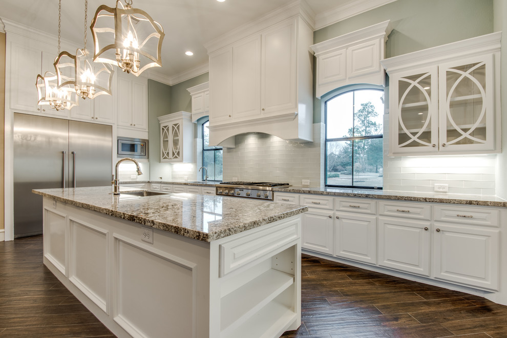 Large tuscan galley ceramic tile and brown floor eat-in kitchen photo in Houston with a single-bowl sink, raised-panel cabinets, white cabinets, granite countertops, white backsplash, glass tile backsplash, stainless steel appliances and an island