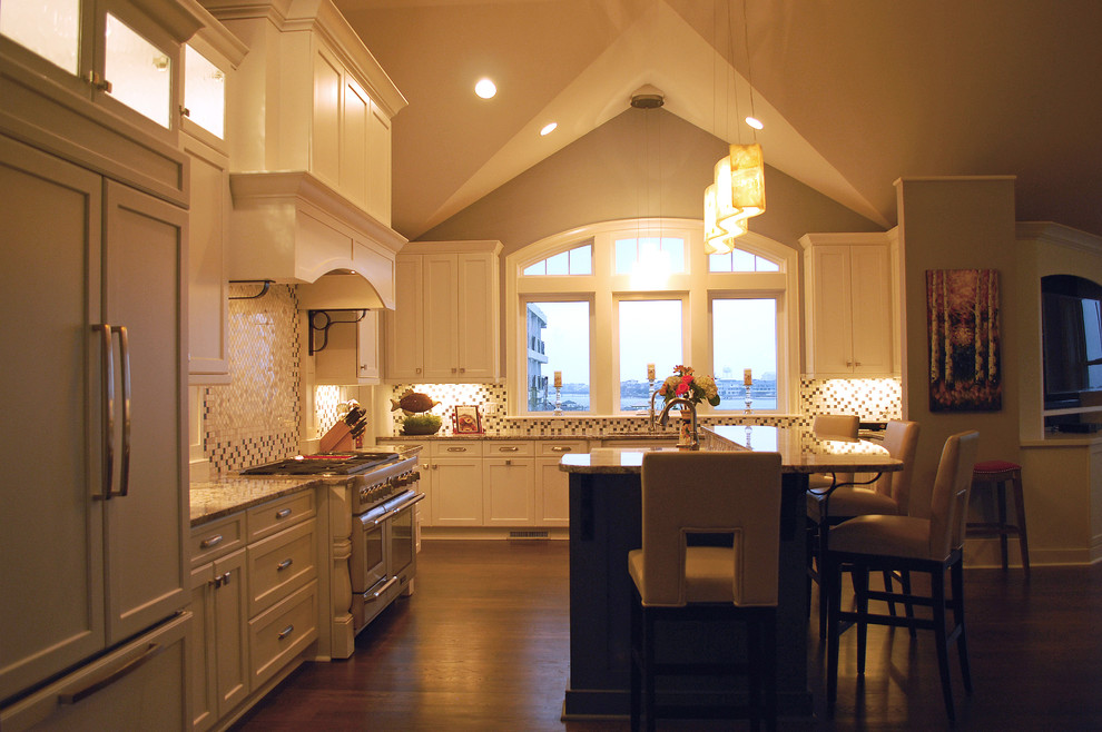 Klassisk inredning av ett stort kök, med en rustik diskho, skåp i shakerstil, vita skåp, vitt stänkskydd, rostfria vitvaror, mörkt trägolv och en köksö