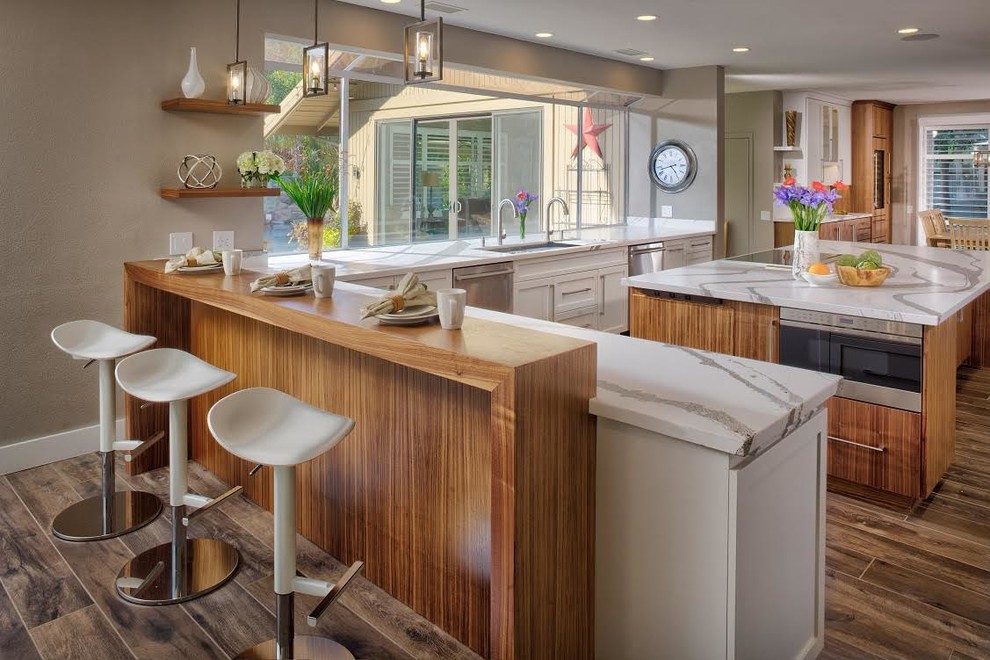 Large classic l-shaped kitchen/diner in Sacramento with a submerged sink, integrated appliances, an island, brown floors, white worktops, flat-panel cabinets, medium wood cabinets, engineered stone countertops and porcelain flooring.