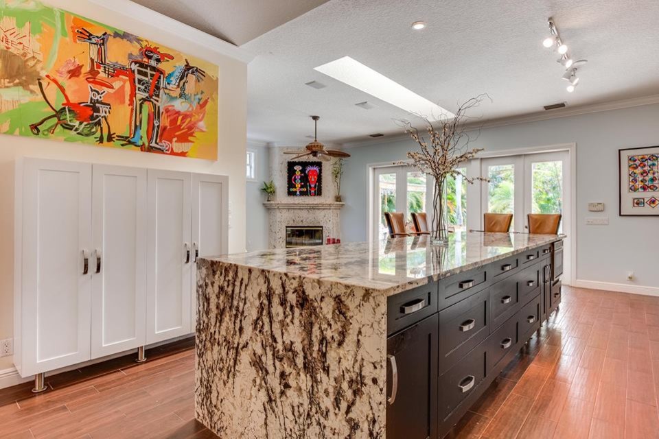 Large trendy l-shaped dark wood floor and red floor eat-in kitchen photo in Miami with an undermount sink, shaker cabinets, white cabinets, granite countertops, multicolored backsplash, stone tile backsplash, stainless steel appliances, an island and brown countertops