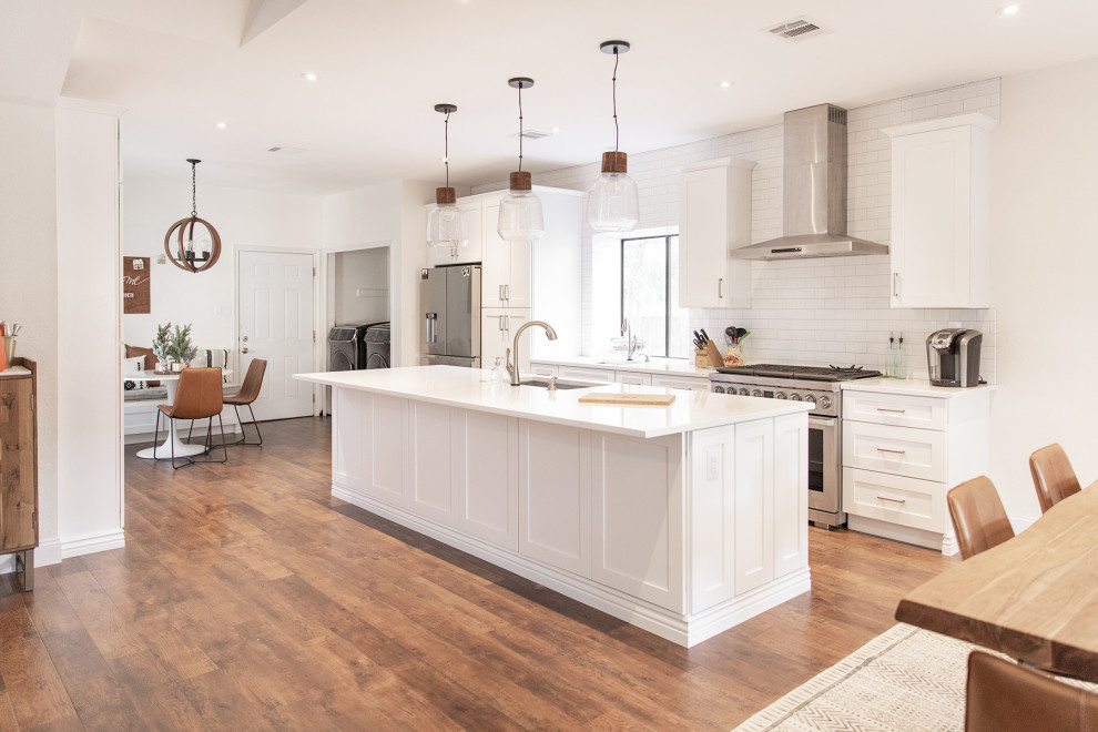 This is an example of a medium sized classic kitchen/diner in Phoenix with shaker cabinets, white cabinets, white splashback, metro tiled splashback, stainless steel appliances, medium hardwood flooring, an island and brown floors.