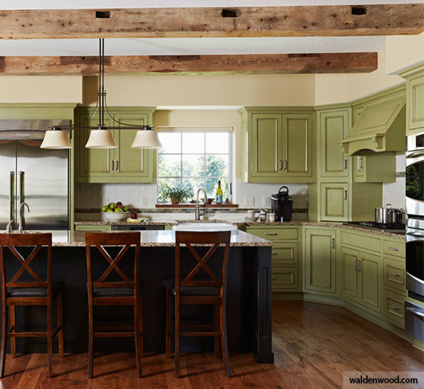 Inredning av ett lantligt kök, med en undermonterad diskho, luckor med upphöjd panel, granitbänkskiva, rostfria vitvaror, mörkt trägolv, en köksö, brunt golv, gröna skåp, vitt stänkskydd och stänkskydd i tunnelbanekakel