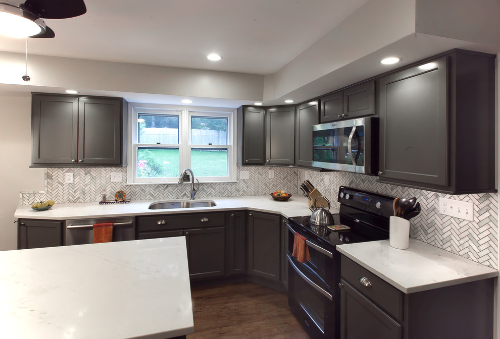 Inspiration for a mid-sized transitional l-shaped vinyl floor and brown floor eat-in kitchen remodel in Philadelphia with an undermount sink, recessed-panel cabinets, gray cabinets, quartz countertops, gray backsplash, marble backsplash, stainless steel appliances and an island