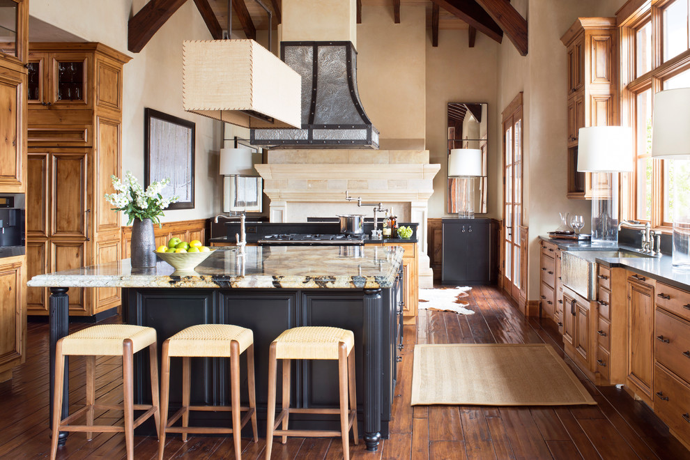 This is an example of a rustic u-shaped kitchen in Denver with a belfast sink, raised-panel cabinets, medium wood cabinets, medium hardwood flooring and an island.