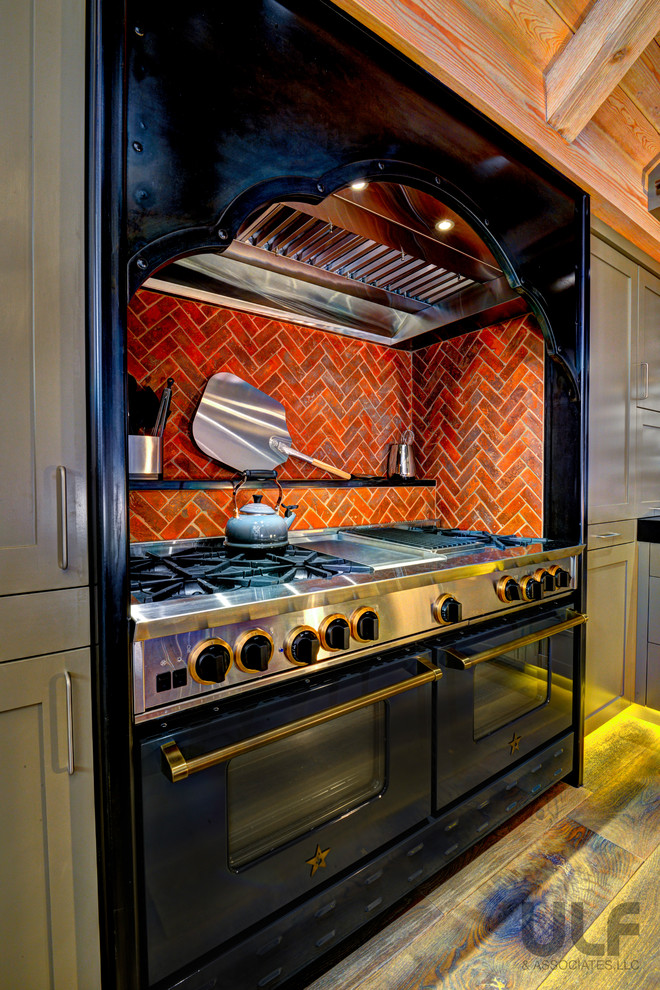 Medium sized rustic kitchen/diner in Denver with recessed-panel cabinets, green cabinets, red splashback, black appliances and dark hardwood flooring.