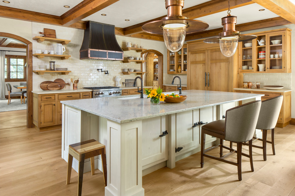 Photo of a rustic kitchen in Denver with a submerged sink, recessed-panel cabinets, medium wood cabinets, beige splashback, metro tiled splashback, integrated appliances and an island.
