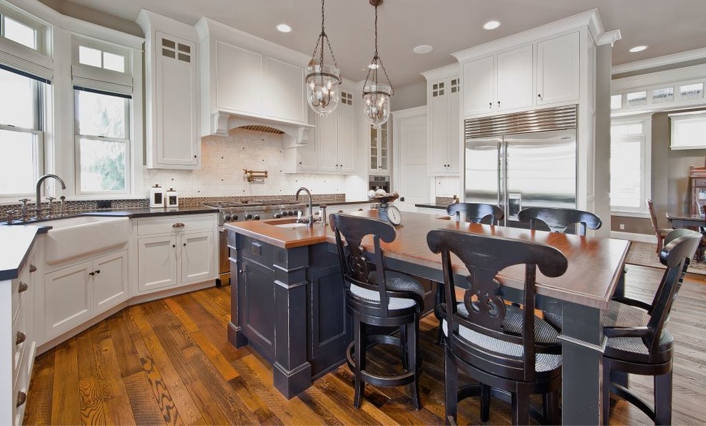 Foto de cocina de estilo americano de tamaño medio con electrodomésticos de acero inoxidable, suelo de madera oscura y una isla