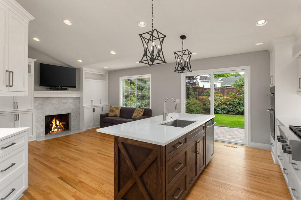 Mid-sized transitional l-shaped medium tone wood floor and brown floor kitchen photo in Portland with an undermount sink, beaded inset cabinets, white cabinets, white backsplash, ceramic backsplash, stainless steel appliances, an island and white countertops