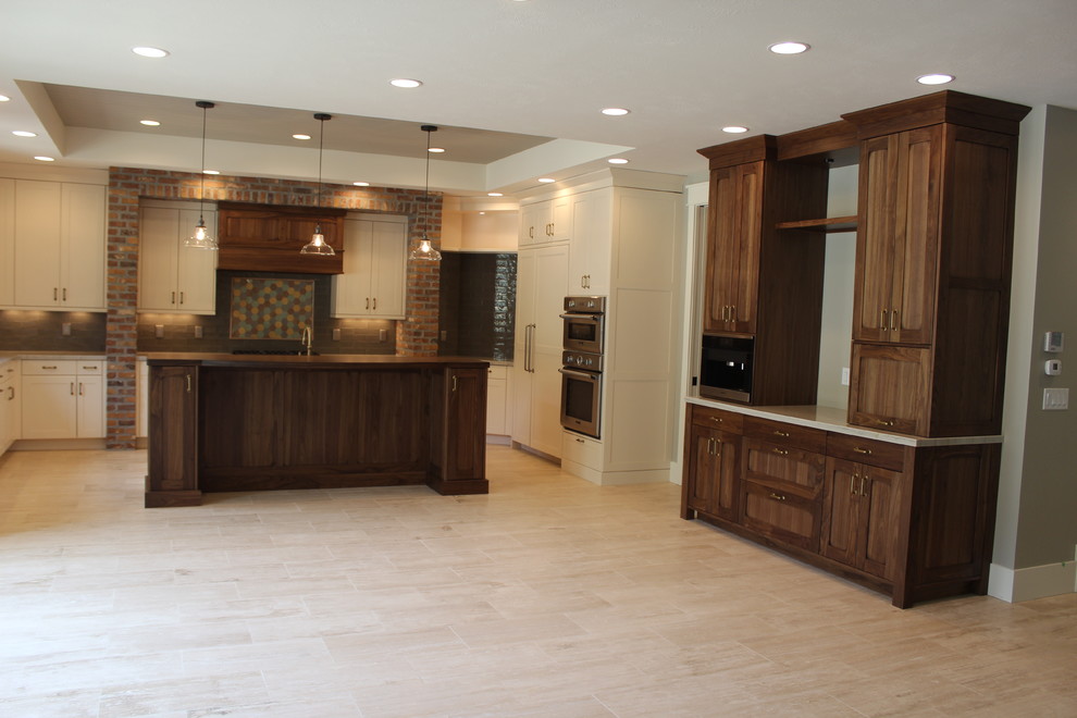 Photo of a large traditional u-shaped open plan kitchen in Salt Lake City with a belfast sink, shaker cabinets, white cabinets, metro tiled splashback, stainless steel appliances and an island.