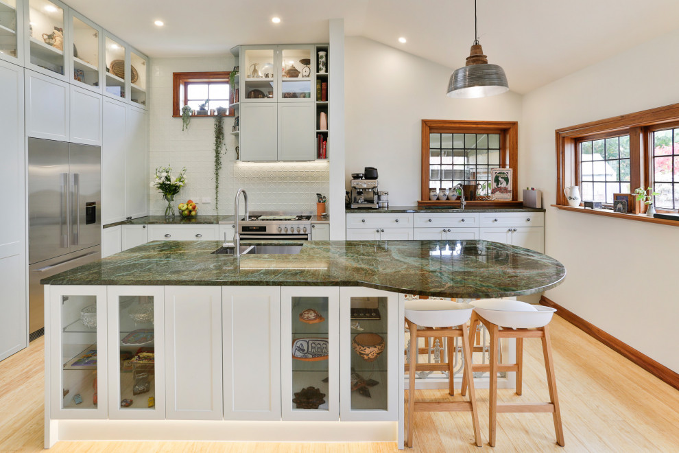 Large traditional l-shaped kitchen/diner in Christchurch with a submerged sink, shaker cabinets, green cabinets, granite worktops, green splashback, metal splashback, stainless steel appliances, bamboo flooring, an island and green worktops.