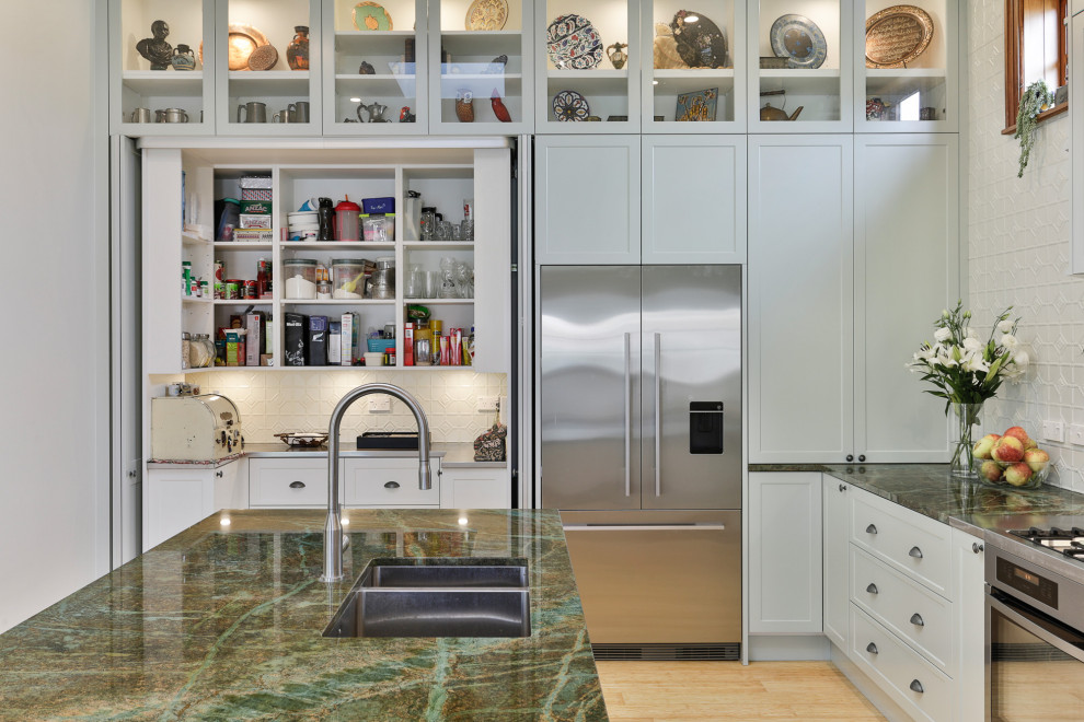 Inspiration for a large classic l-shaped kitchen pantry in Christchurch with a submerged sink, shaker cabinets, green cabinets, granite worktops, green splashback, metal splashback, stainless steel appliances, bamboo flooring, an island and green worktops.