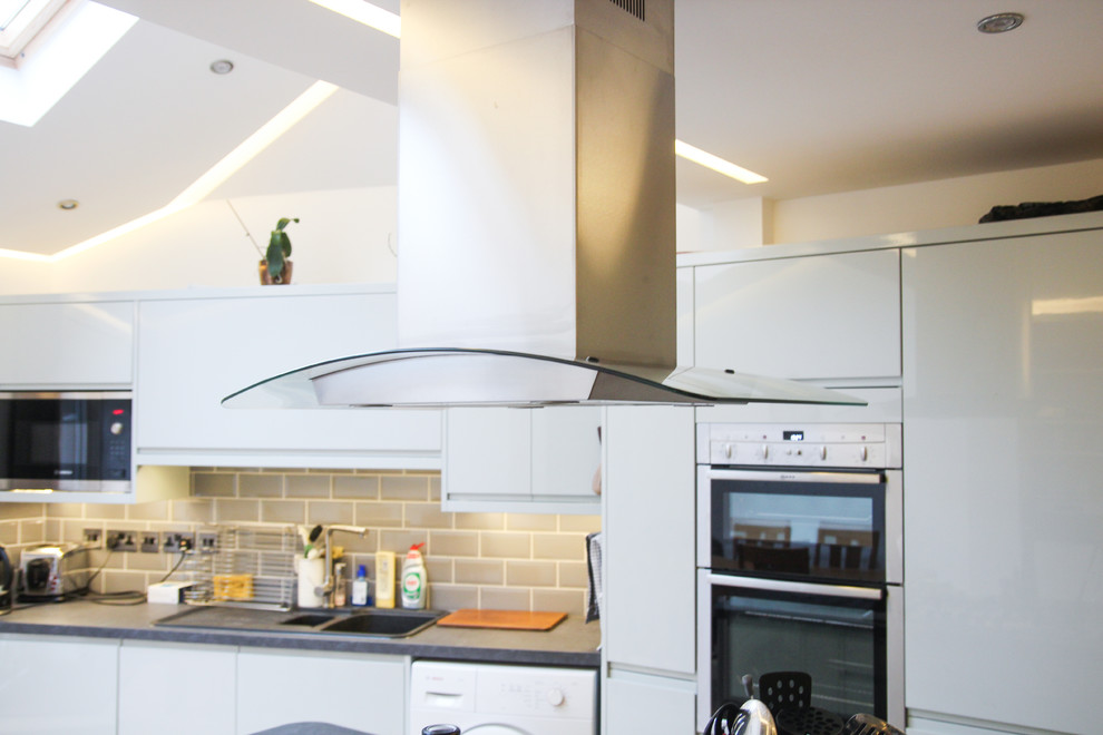 Modern inredning av ett litet linjärt kök och matrum, med grå skåp, bänkskiva i kvartsit, grått stänkskydd, ljust trägolv och en köksö