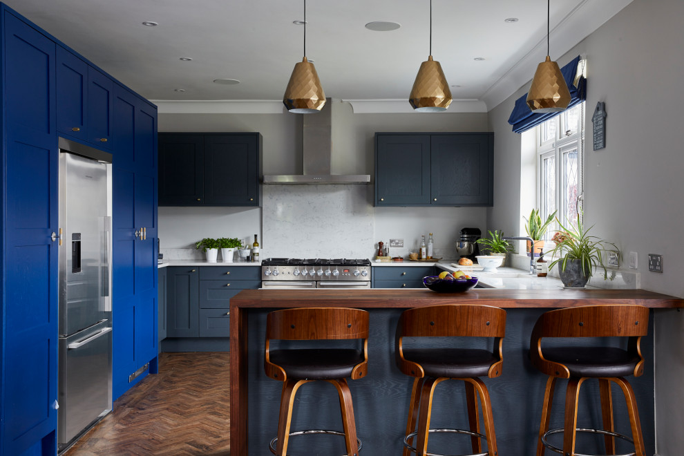 This is an example of a medium sized eclectic u-shaped kitchen/diner in Other with blue cabinets, quartz worktops, stainless steel appliances and a breakfast bar.