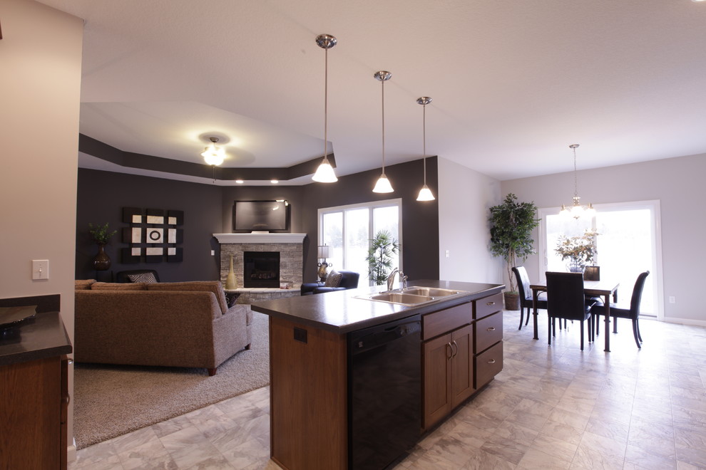 This is an example of a large traditional u-shaped open plan kitchen in Other with shaker cabinets, medium wood cabinets, laminate countertops, black appliances, a double-bowl sink, ceramic flooring, an island and black floors.