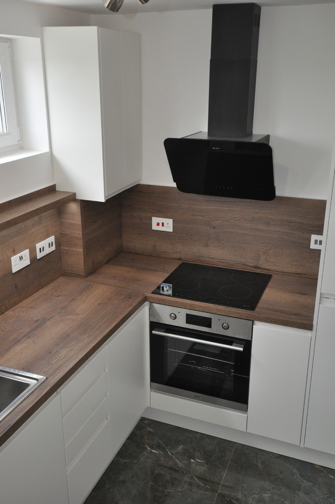 Photo of a medium sized contemporary u-shaped enclosed kitchen in London with a single-bowl sink, flat-panel cabinets, white cabinets, laminate countertops, brown splashback, black appliances, porcelain flooring, no island, green floors and brown worktops.
