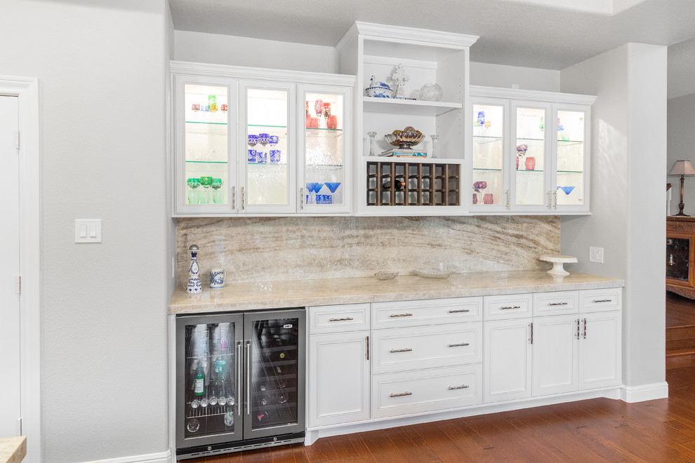 Inspiration for a mid-sized transitional l-shaped light wood floor and orange floor home bar remodel in Houston with recessed-panel cabinets, white cabinets, quartzite countertops, white backsplash, subway tile backsplash and multicolored countertops