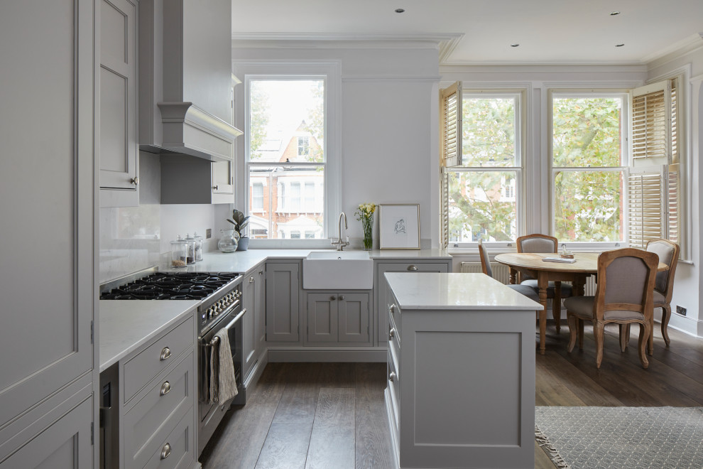 Small classic l-shaped open plan kitchen in London with a belfast sink, grey cabinets, granite worktops, grey splashback, granite splashback, integrated appliances, dark hardwood flooring, an island, brown floors, grey worktops, a coffered ceiling and beaded cabinets.