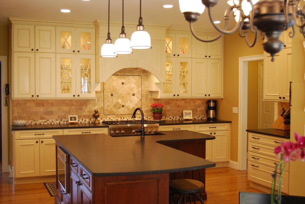 Exempel på ett avskilt, stort klassiskt u-kök, med en rustik diskho, luckor med infälld panel, vita skåp, granitbänkskiva, stänkskydd i tunnelbanekakel, integrerade vitvaror, ljust trägolv och en köksö