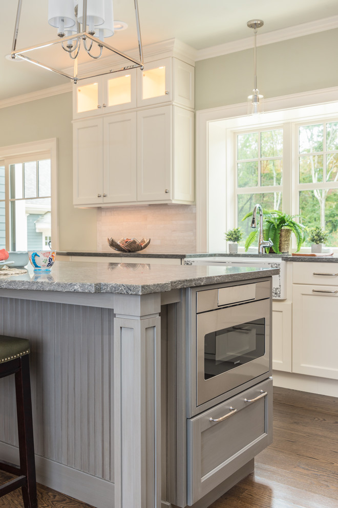 Exempel på ett stort klassiskt grå grått kök, med en rustik diskho, luckor med infälld panel, beige skåp, bänkskiva i kvartsit, beige stänkskydd, stänkskydd i stenkakel, integrerade vitvaror, mörkt trägolv, en köksö och brunt golv