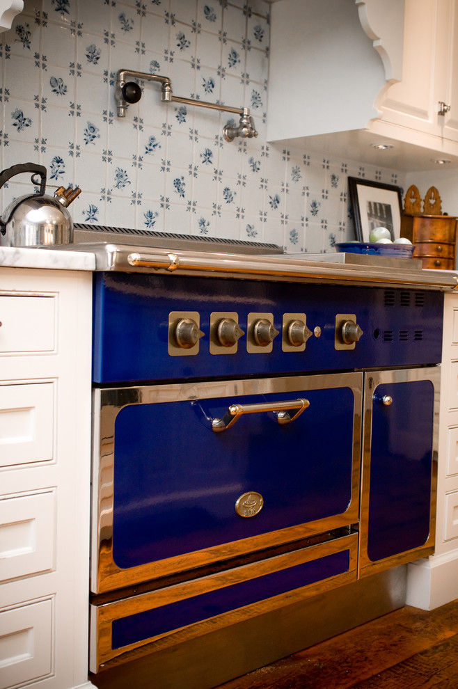 Photo of a medium sized country single-wall kitchen/diner in Manchester with a single-bowl sink, white cabinets, marble worktops, medium hardwood flooring, coloured appliances, raised-panel cabinets, blue splashback, ceramic splashback and a breakfast bar.