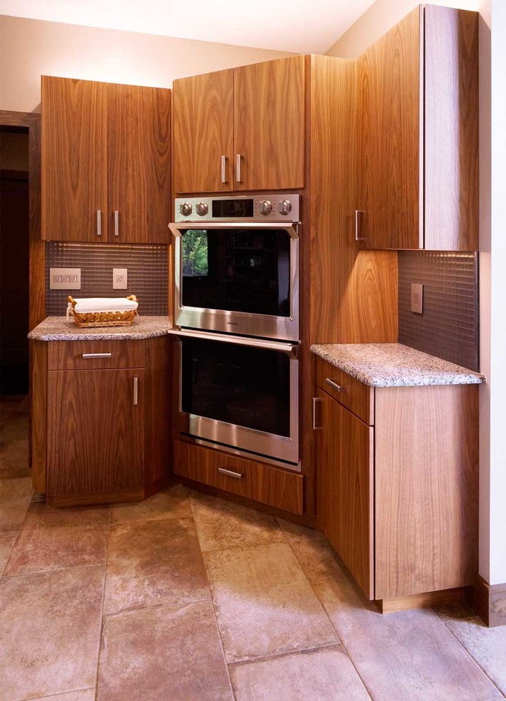 Foto på ett stort funkis flerfärgad kök, med en undermonterad diskho, släta luckor, skåp i mellenmörkt trä, granitbänkskiva, grått stänkskydd, stänkskydd i metallkakel, rostfria vitvaror, klinkergolv i keramik, en köksö och beiget golv